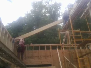 Carpenter raising a rafter beam on a new second story frame in Fountain