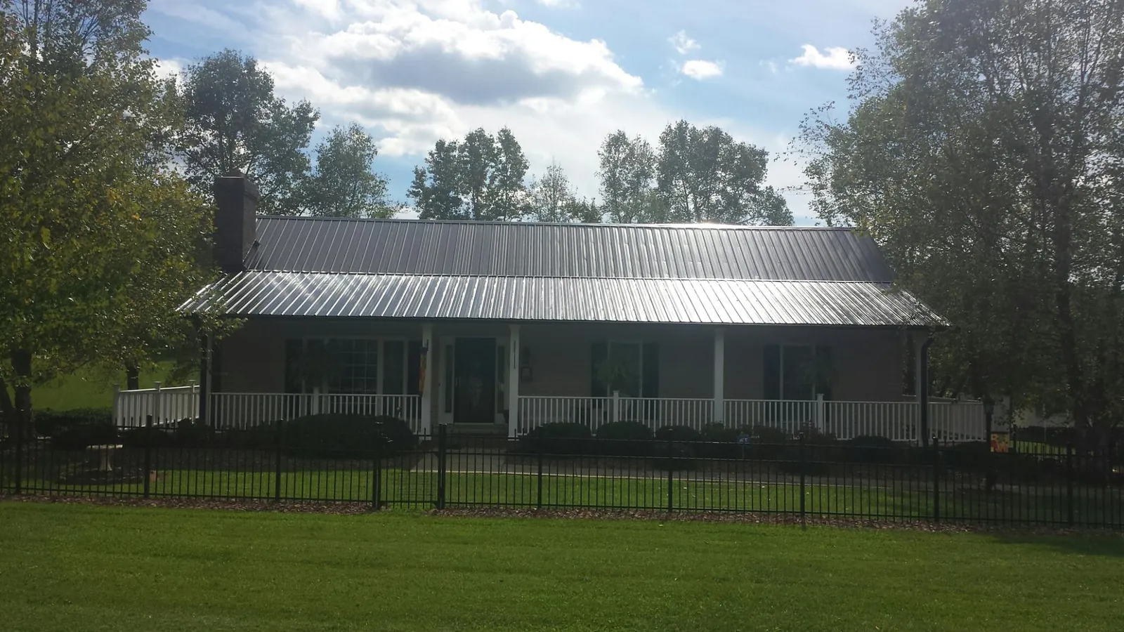 Gray metal roof on a brick ranch with a full width front porch — Gutter Guard Installation work by our crew in Fountain
